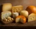 Variedad de quesos europeos sobre tabla de madera: curados, azules, con agujeros y corteza lavada